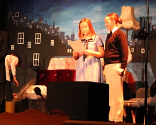 students on stage reading from script